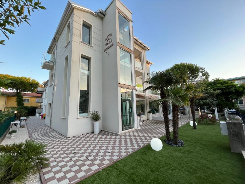a white building with a green lawn in front of it at Villa Liliana in Cervia