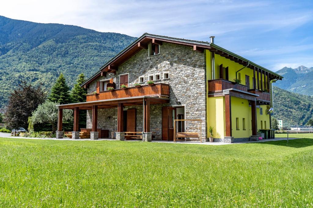 a house in a field with mountains in the background at Il Bisteca in Morbegno