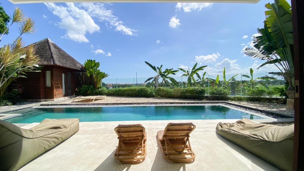 a swimming pool with two lounge chairs and a swimming pool at Villa Dew Canggu in Kerobokan