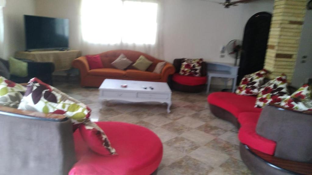 a living room with red couches and a tv at الساحل الشمالي in Borg El Arab