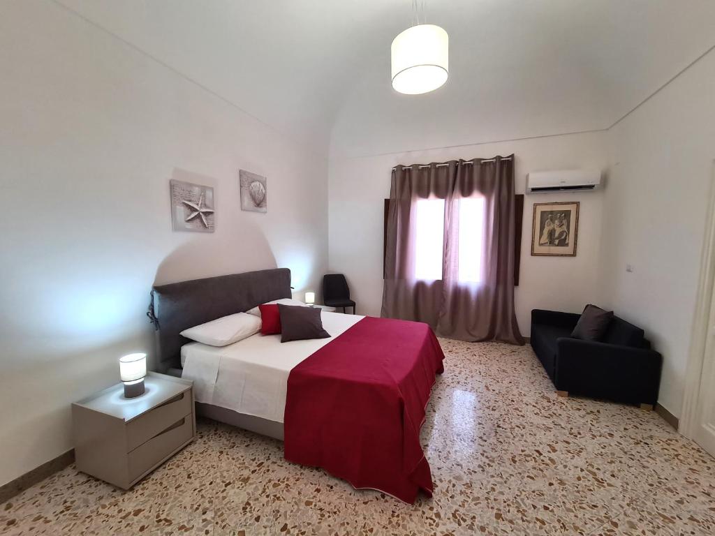 a bedroom with a bed and a chair and a window at Casa Lara in Castellammare del Golfo