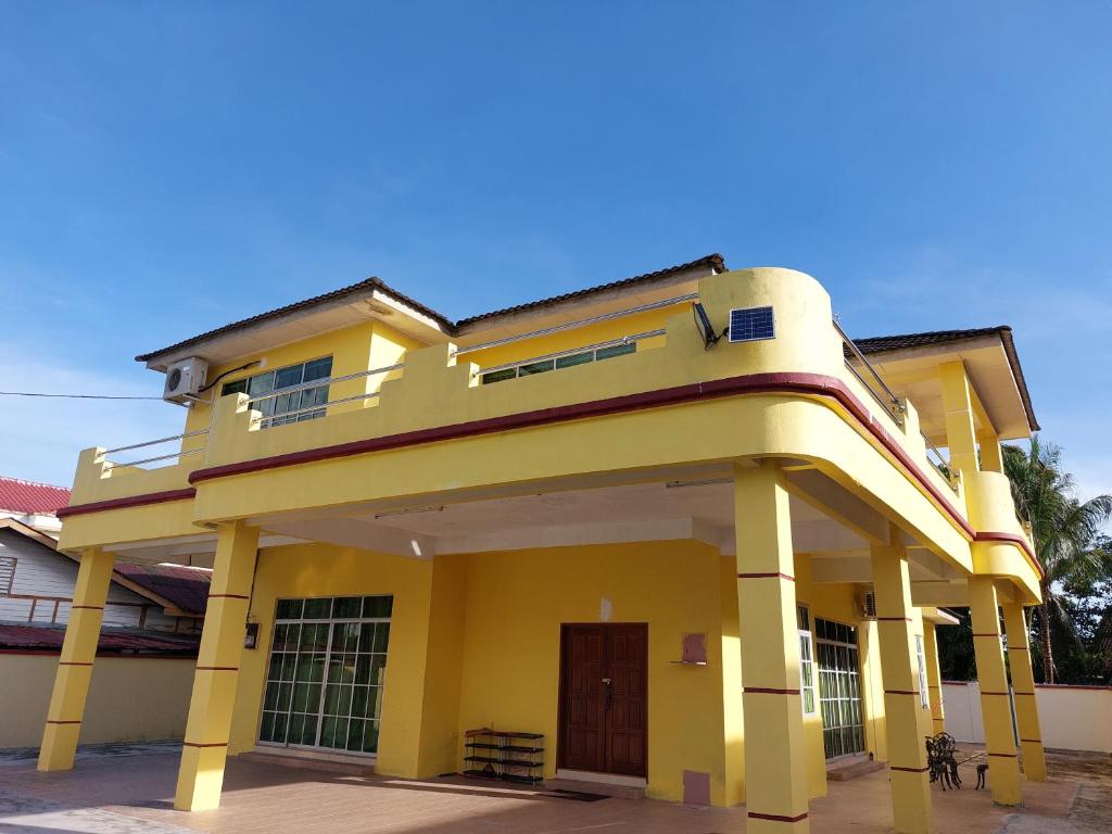 une maison jaune avec une grande cour avant dans l'établissement AL' Indara Bunglow Homestay Taiping, à Taiping