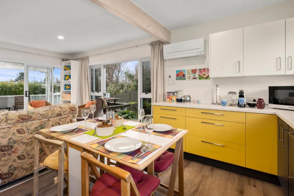 a kitchen with a wooden table and yellow cabinets at Plum Tree Cottage - Turangi Holiday Home in Turangi