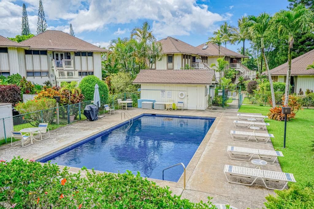 a swimming pool in a yard with chairs and a house at Paniolo #202A in Princeville