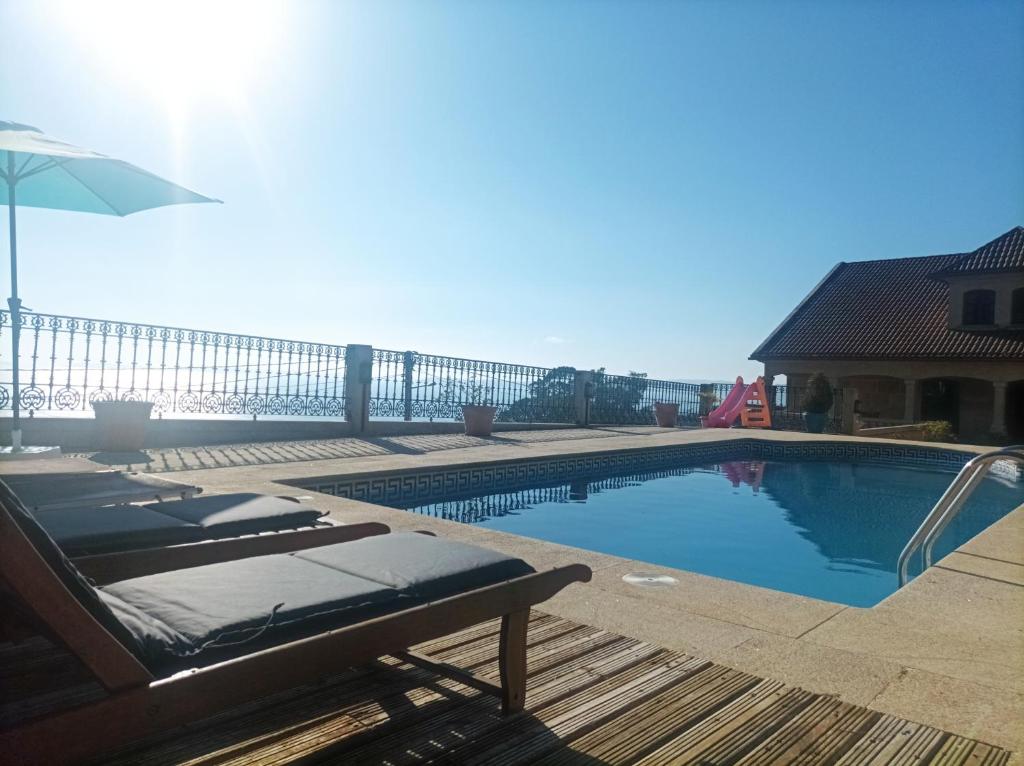 a swimming pool with chairs and an umbrella at Villa María in Ardán