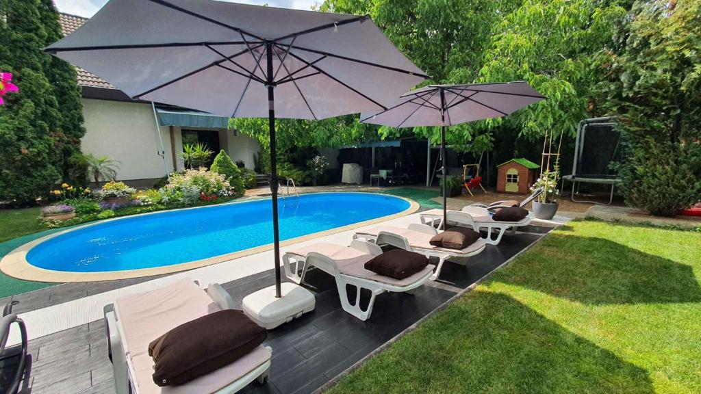 a group of chairs and umbrellas next to a pool at Holiday home in Siofok - Balaton 19950 in Siófok