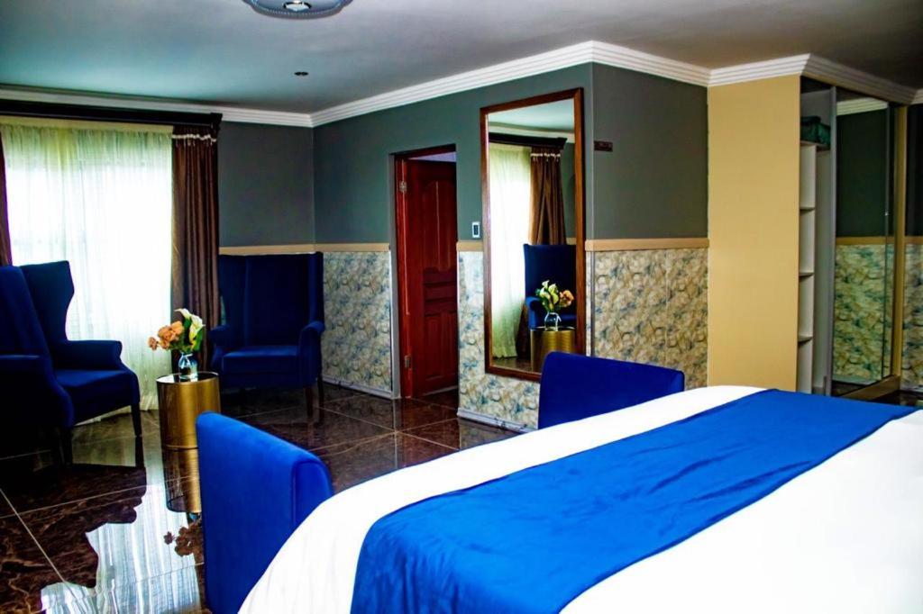 a bedroom with a blue bed and blue chairs at Xilumani Hotel in Giyani