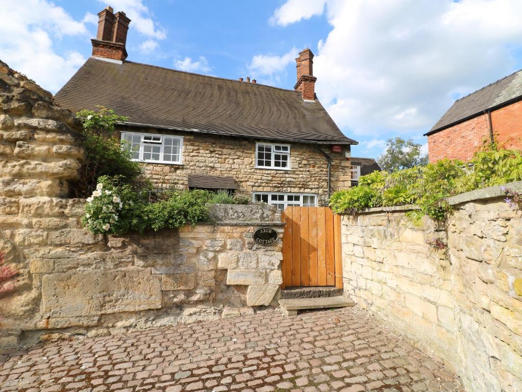 an old stone house with a wooden door on a wall at Arch Cottage in Lincoln