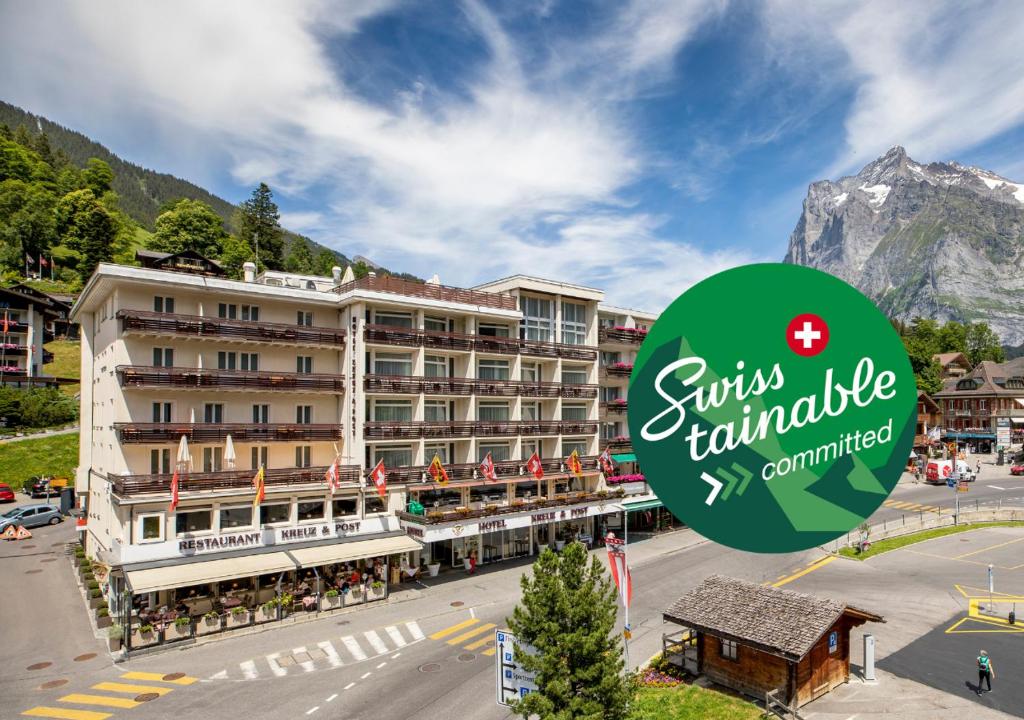 ein Hotel in den Bergen mit einem Schild, auf dem das Krisen-Franchise steht in der Unterkunft Hotel Kreuz&Post**** Grindelwald in Grindelwald