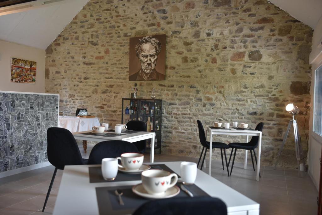 a restaurant with tables and chairs and a brick wall at Epicurieux Normand in Viessoix