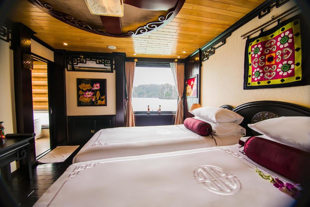 two twin beds in a room with a window at Dragon Legend Cruise in Ha Long