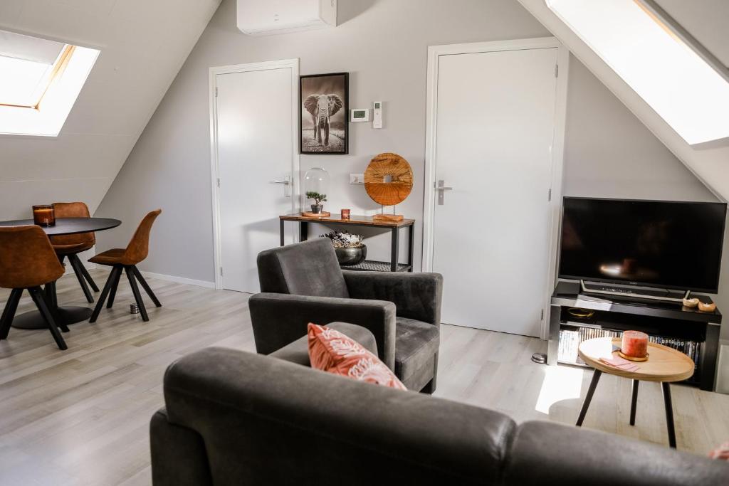 - un salon avec un canapé et une télévision dans l'établissement Appartement op de 1e verdieping., à Wemeldinge