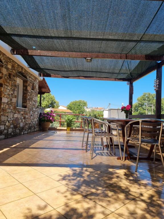 a patio with chairs and a table with a blue roof at I Avli tou Valsakia in Raches