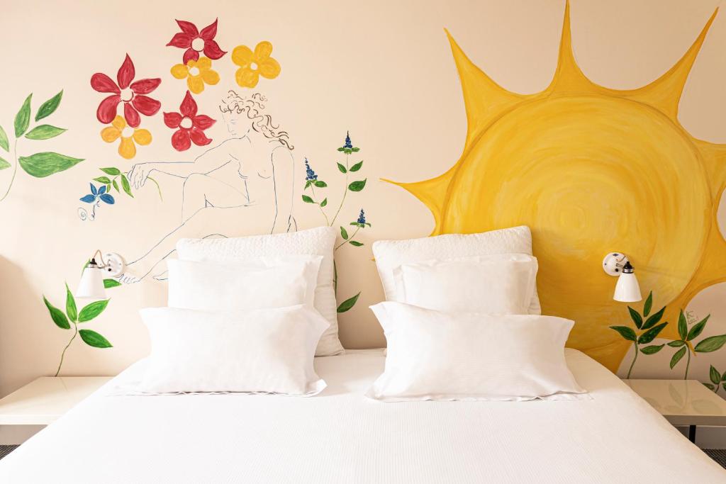 1 dormitorio con 1 cama con sol y flores en la pared en Hôtel Arvor Saint Georges, en París