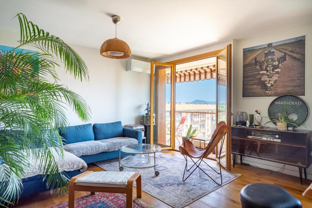 een woonkamer met een blauwe bank en een tafel bij Large 1 bedroom close to the beach with AC and terrace - Dodo et Tartine in Toulon