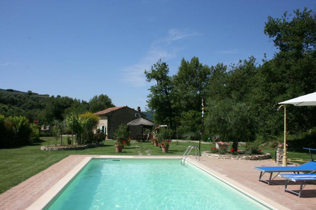 a swimming pool with two blue chairs and a house at Casa di Pino in Polvano