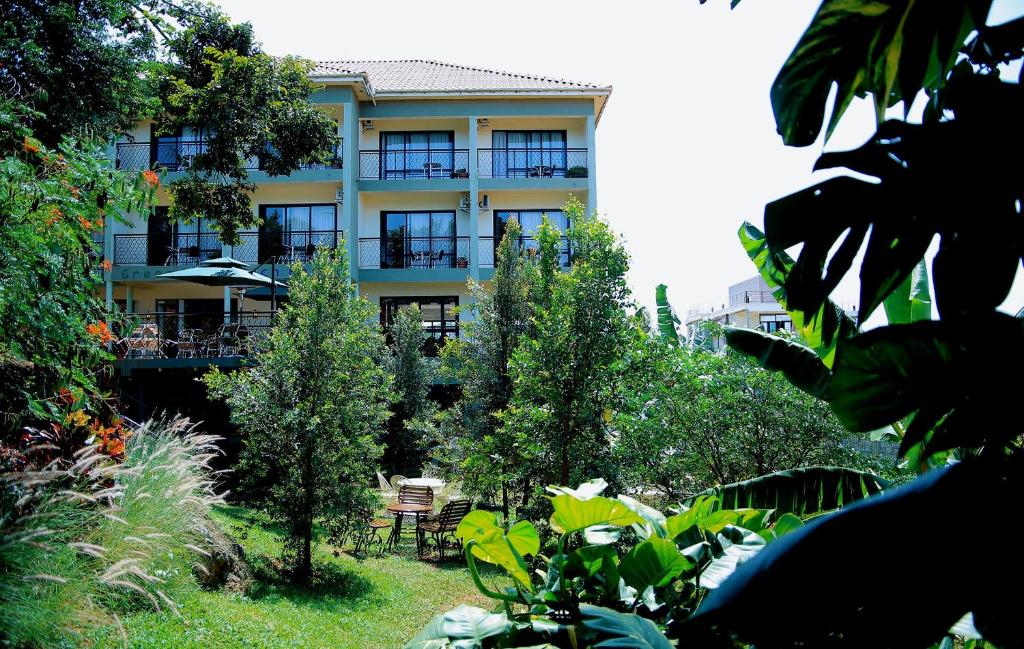 ein Gebäude mit Tischen und Stühlen in einem Garten in der Unterkunft Greenyard Beach Hotel in Entebbe