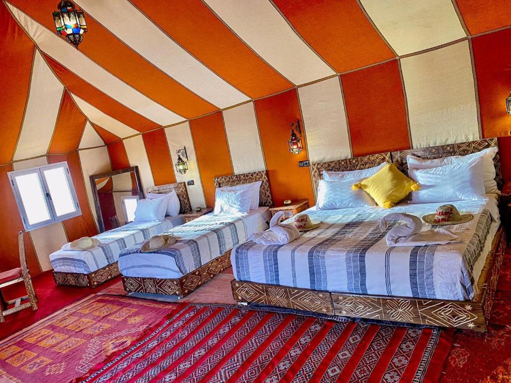 a room with three beds and a striped wall at Desert Heart Luxury Camp in Merzouga