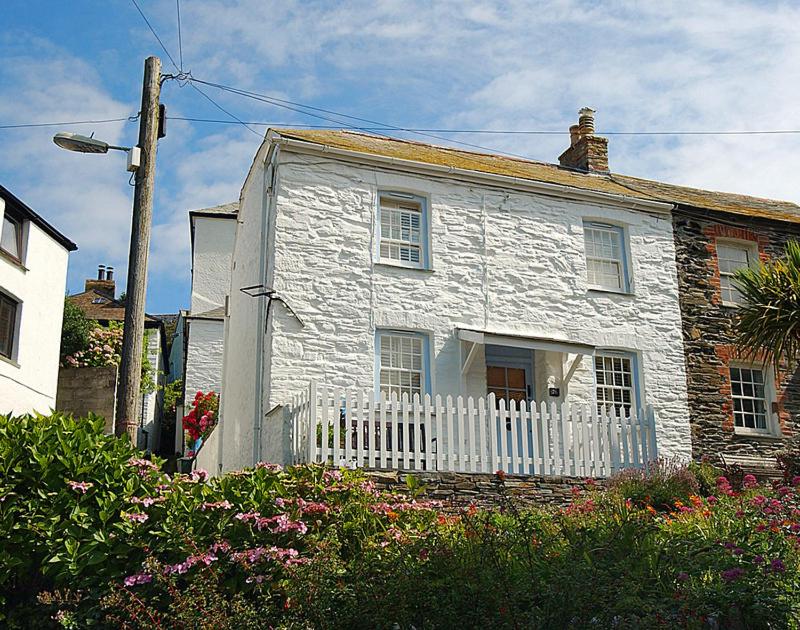 a white house with a white fence and flowers at Homelands in Port Isaac