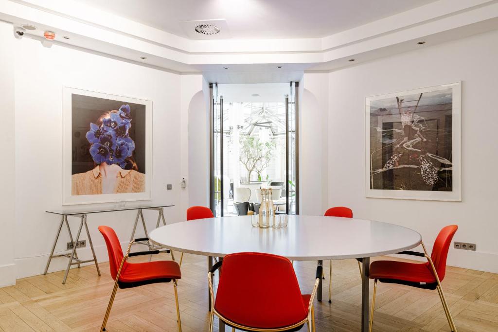 a dining room with a white table and red chairs at H15 Boutique Hotel, Warsaw, a Member of Design Hotels in Warsaw