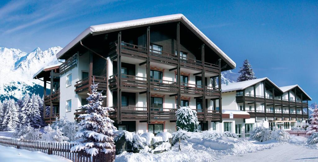 duży budynek z śniegiem na ziemi w obiekcie Clubhotel Götzens w mieście Innsbruck