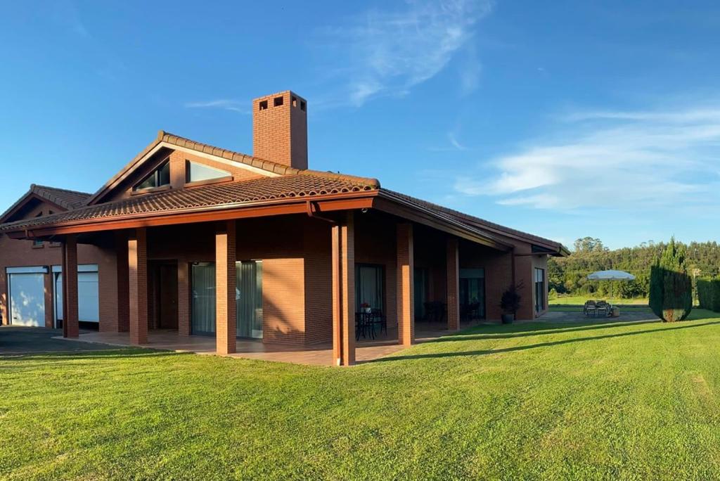 una casa con un césped verde delante de ella en Villa Monasterio, en Camargo