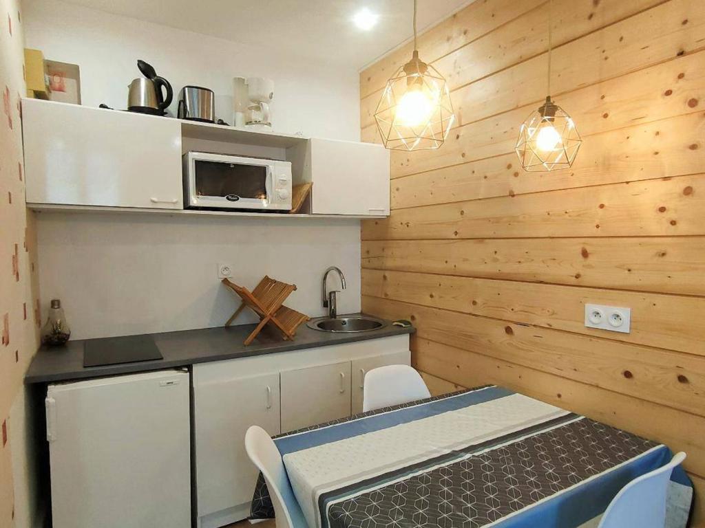 une petite cuisine avec une table et un micro-ondes dans l'établissement Appartement cosy avec balcon, proche thermes et télécabine, Cauterets - FR-1-234-135, à Cauterets