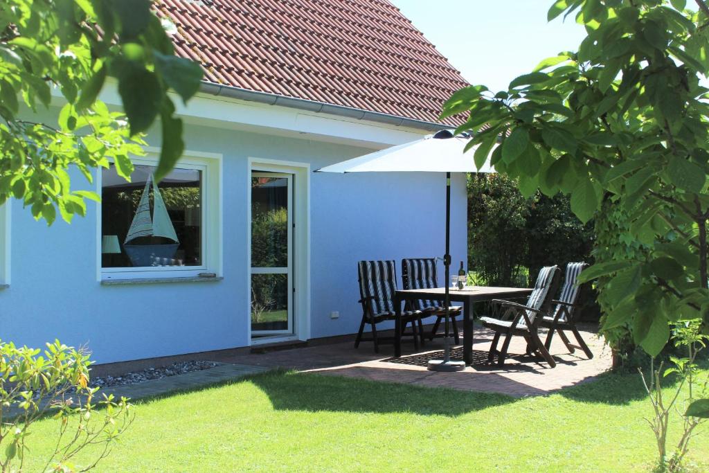 a blue house with a table and chairs and an umbrella at Haus Wiekend - Fewo Knurrhahn in Wiek auf Rügen 