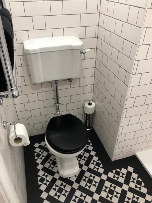 a bathroom with a toilet with a black seat at The Beetroot in Margate
