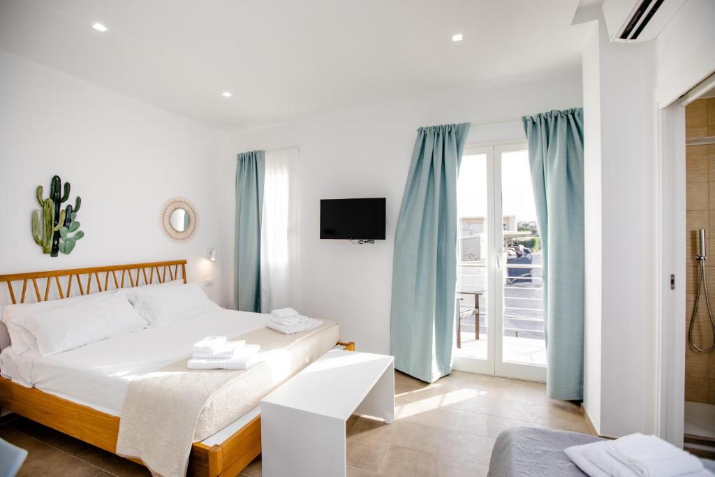 Biała sypialnia z łóżkiem i balkonem w obiekcie Kaary BellaVita Superior Room w mieście Marzamemi
