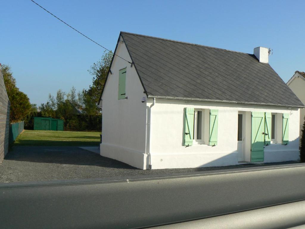une maison blanche avec des fenêtres vertes à volets près d'une rue dans l'établissement Les volets verts, au Crotoy
