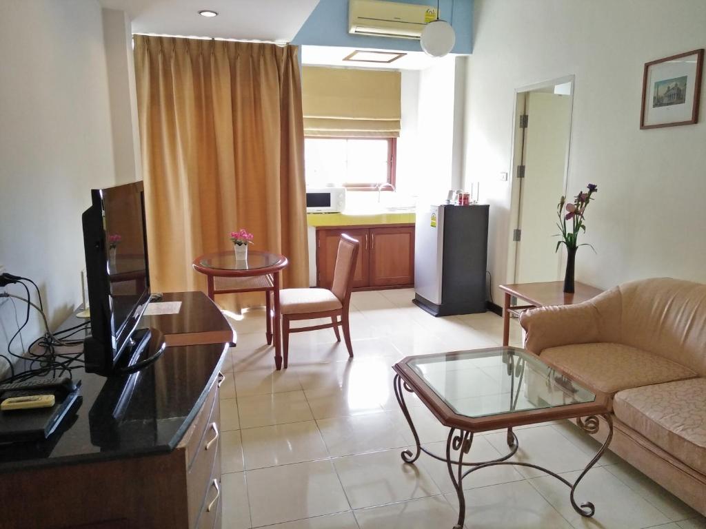 A suite-style living area with a sofa, television, kitchenette, refrigerator and window.