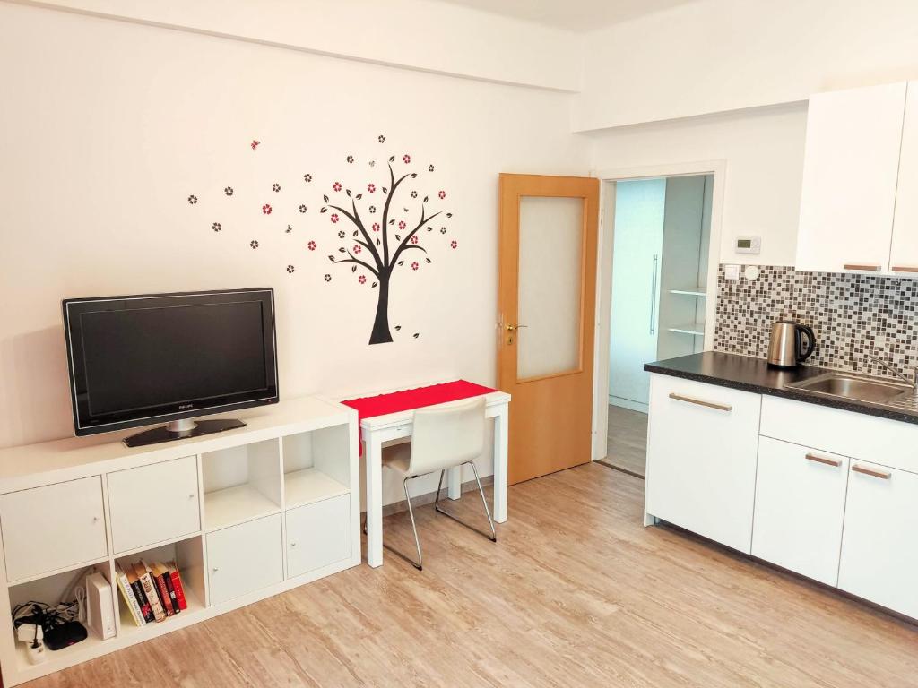 a kitchen with a table with a tv and a tree on the wall at Apartment Žižkov in Prague