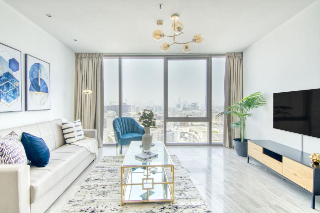 a living room with a white couch and a tv at GuestReady - A View of the City Skyline - D1 Tower in Dubai