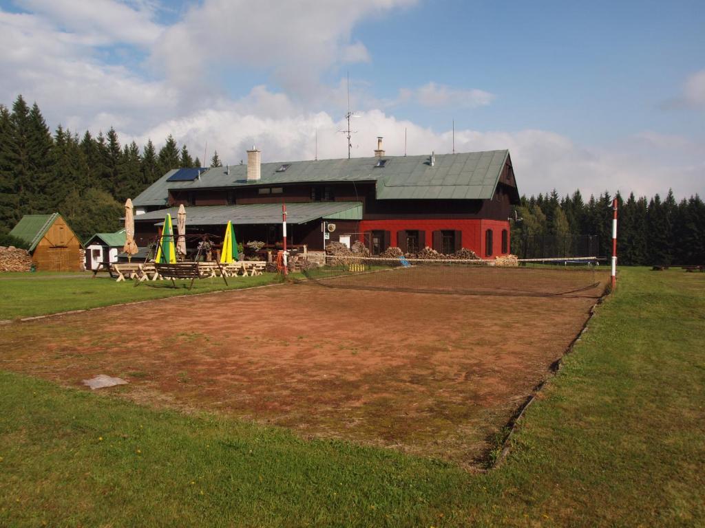um grande celeiro vermelho com um campo à sua frente em Modrokamenná bouda em Janske Lazne