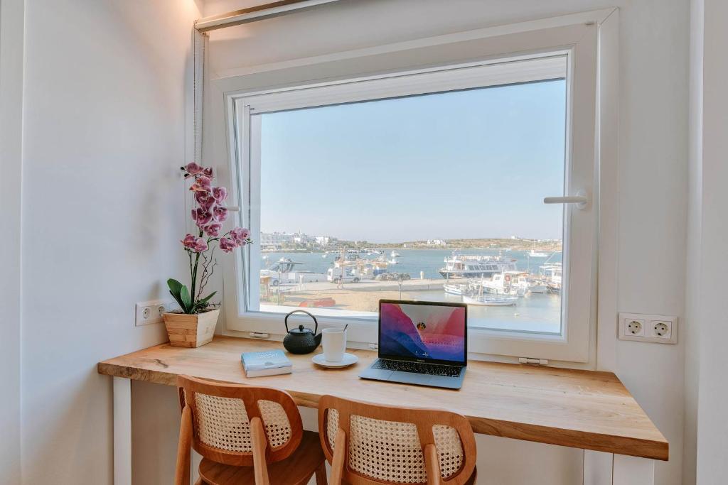 a laptop computer sitting on a desk in front of a window at Nautica Suites - Modern Seaview Suite in Antiparos