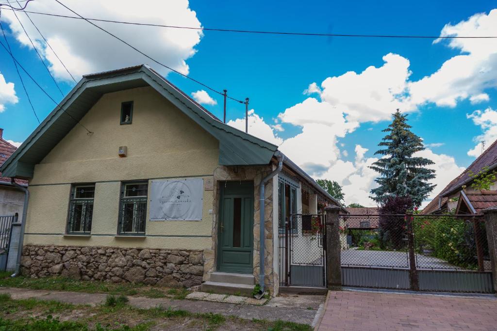 una pequeña casa amarilla con una puerta verde en Szívem Csücske Vendégház, en Nagybörzsöny