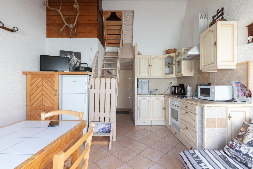 a kitchen with white cabinets and a spiral staircase at L'Alpiniste in Ancelle