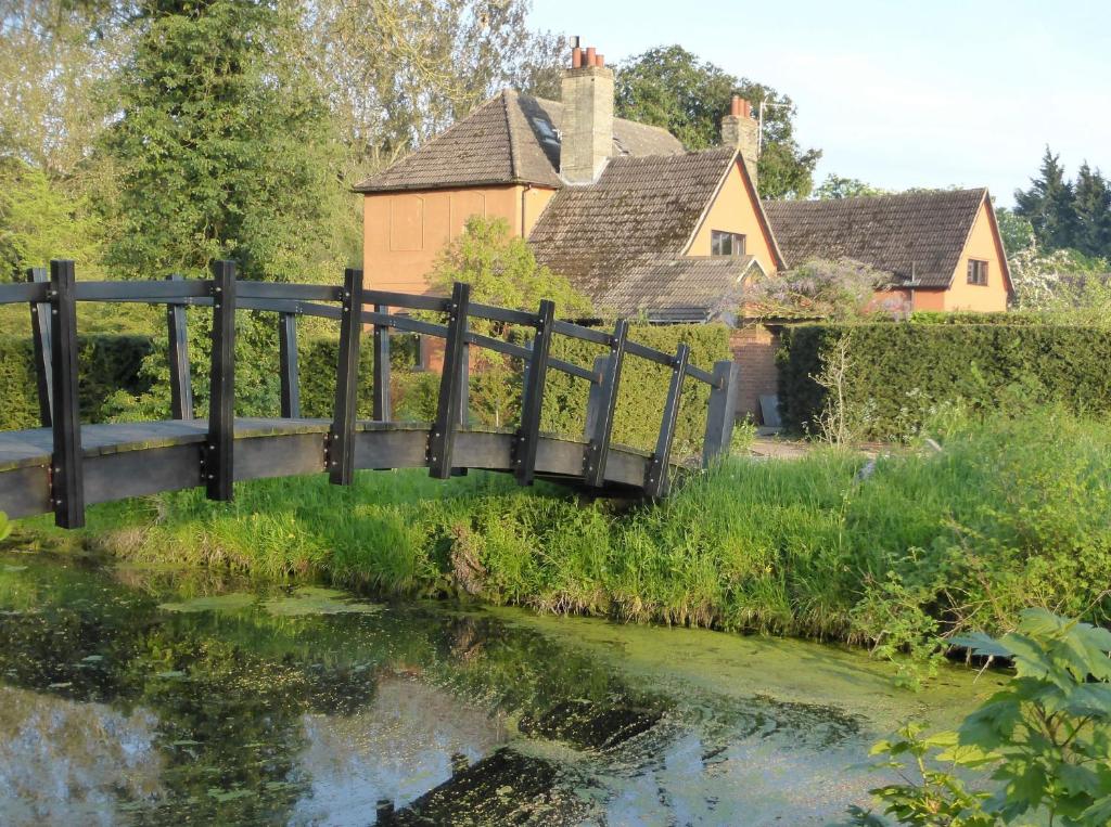 a wooden bridge over a river with houses in the background at The School Room in Stowmarket