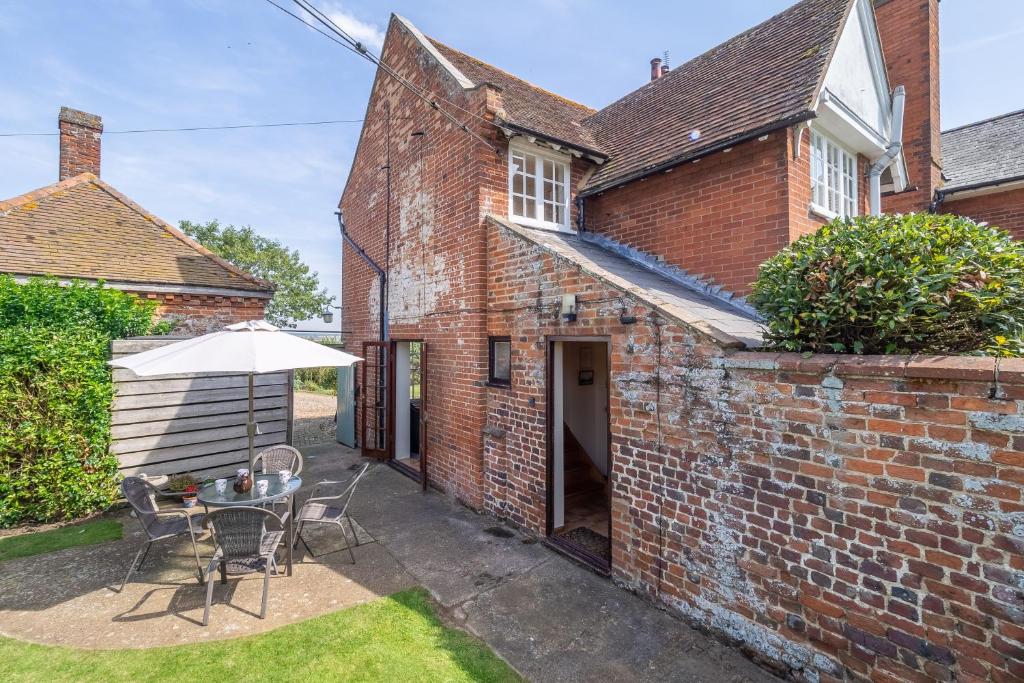 an old brick house with a table and an umbrella at Honeypot Cottage in Ipswich