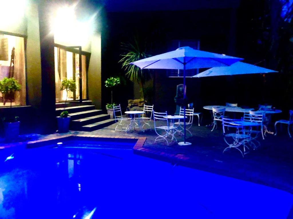 a patio with tables and umbrellas next to a pool at Absolut Guest Boutique in Centurion