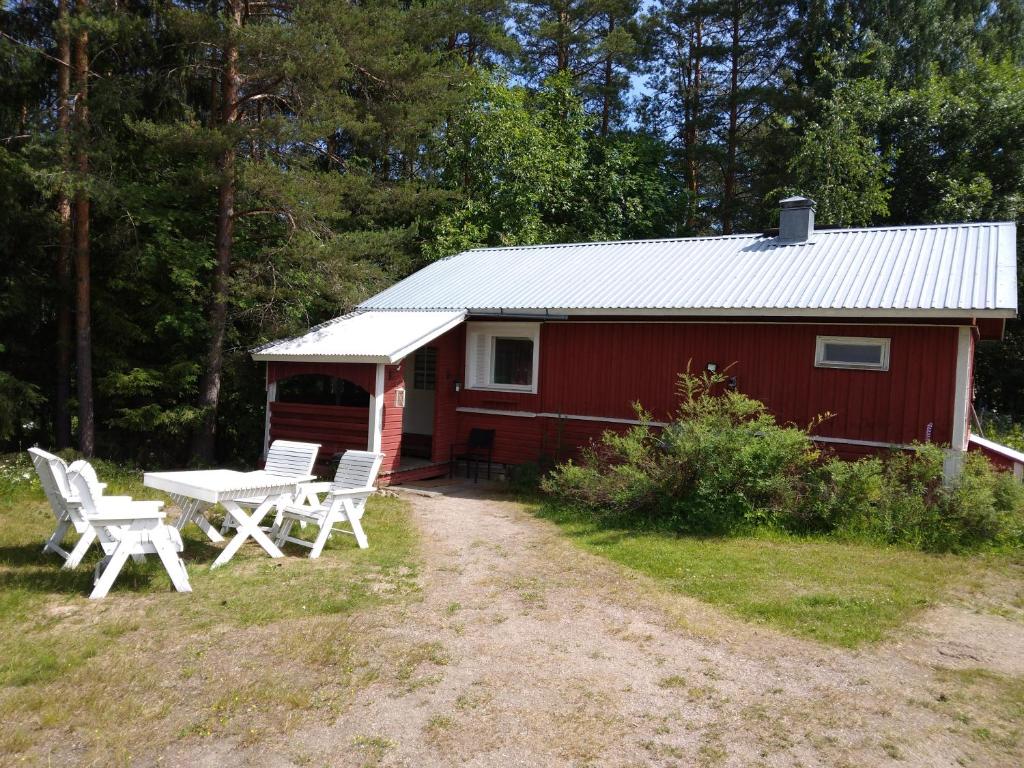 a red cabin with a picnic table and chairs in front of it at Miekkalan Saunatupa in Lappeenranta