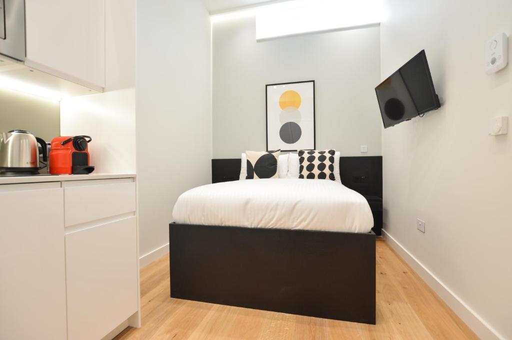 ein kleines Schlafzimmer mit einem schwarzen und weißen Bett in der Unterkunft Earls Court West Serviced Apartments by Concept Apartments in London