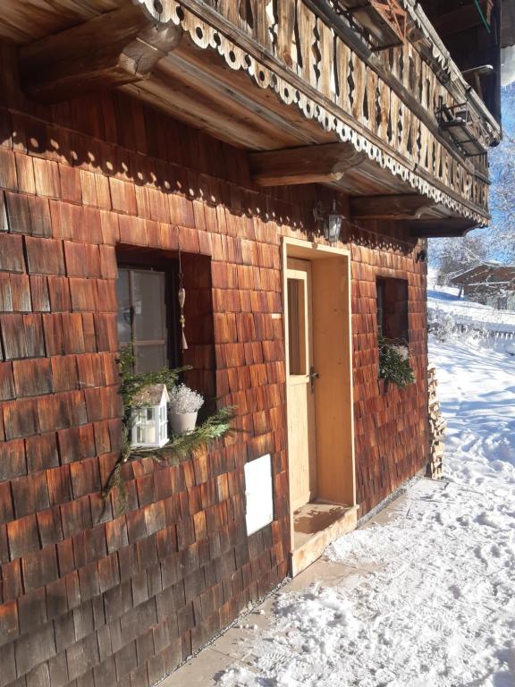 a brick building with a door in the snow at Hüttenzauber in Taxenbach