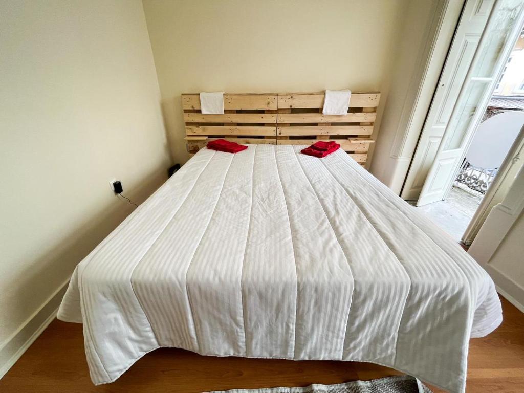 a white bed with two red pillows on it at Sweet Love Family Budget in Coimbra