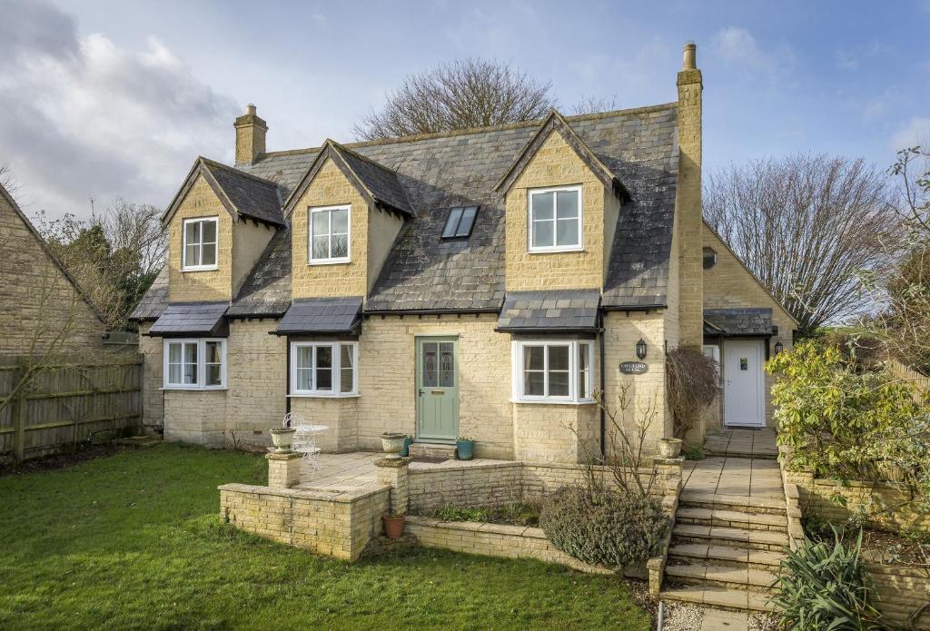 a large brick house with a green door at Upper End House in Shipton under Wychwood