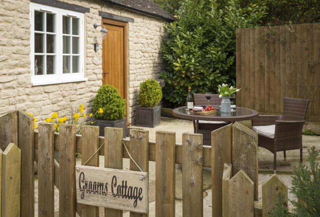 una valla de madera con una mesa en un jardín en Grooms Cottage, en Kingham