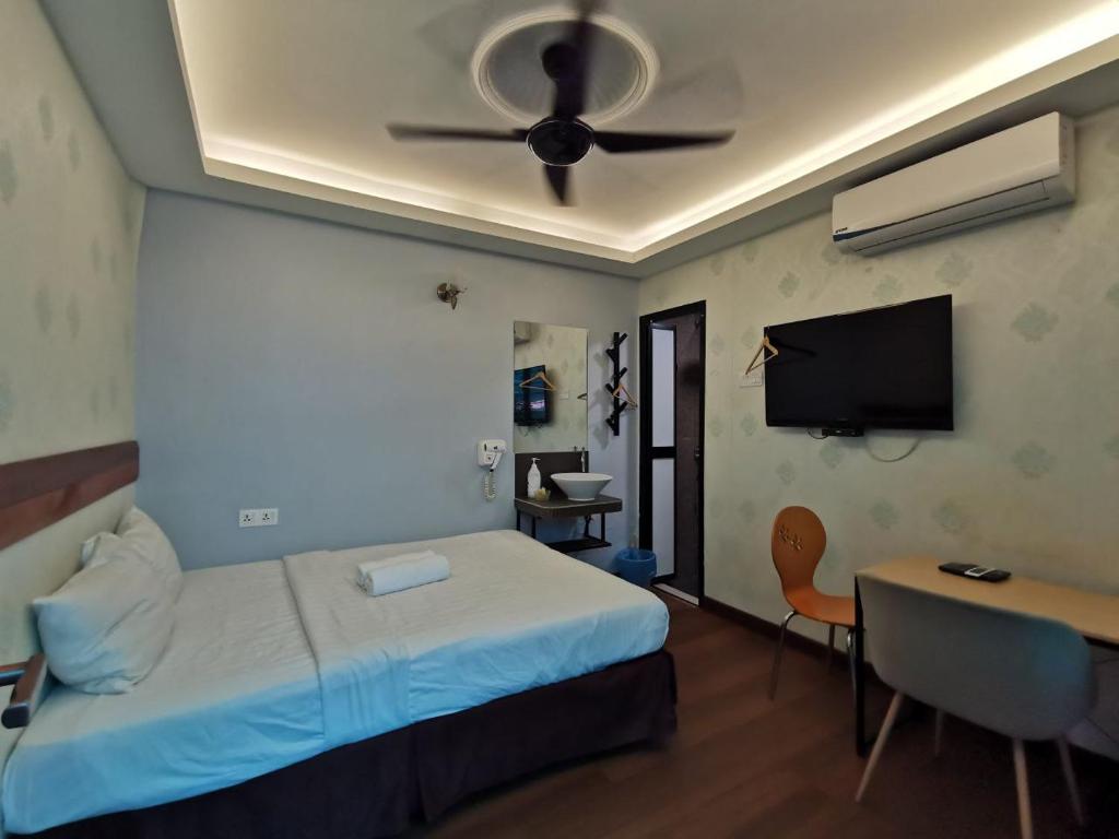 a bedroom with a bed with a ceiling fan and a desk at Cheras-Miharja Homestay @Sunway Velocity in Kuala Lumpur