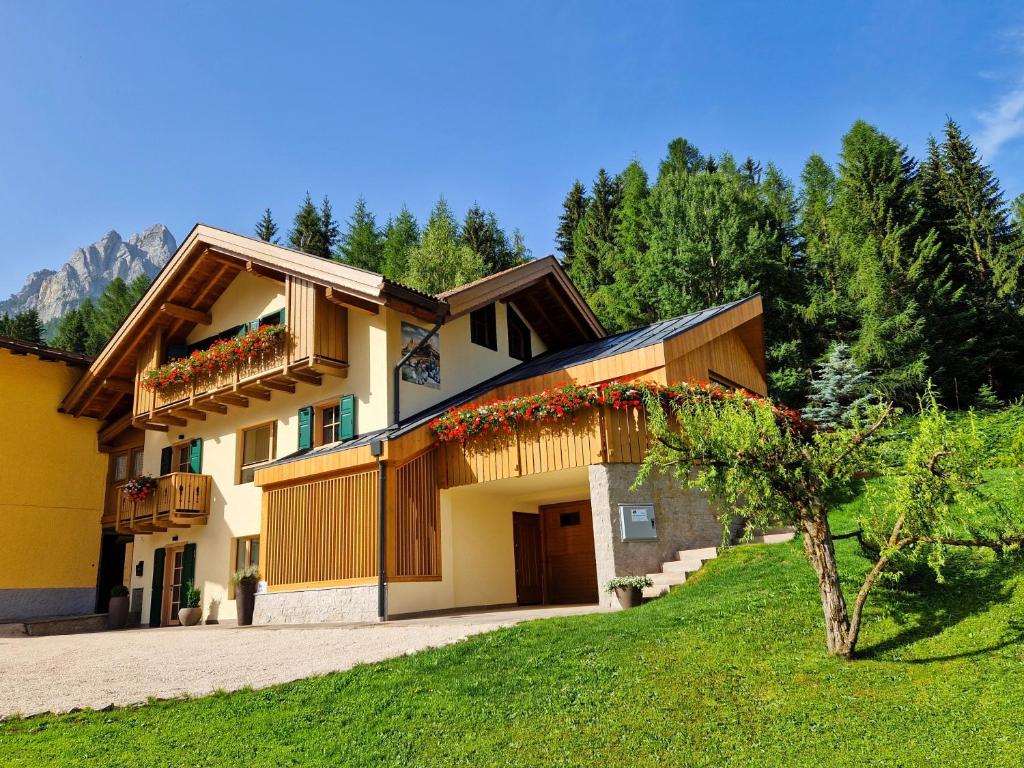una casa con balcone e albero di Chalet La Ciaseta a Pozza di Fassa