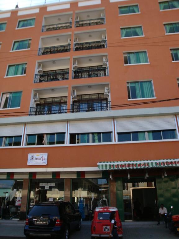 ein orangefarbenes Gebäude mit davor geparkt in der Unterkunft Evergreen Hotel in Antananarivo